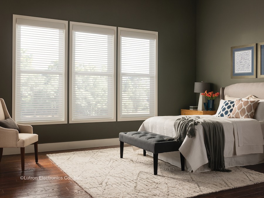 A bedroom with windows equipped with smart shades by Lutron.