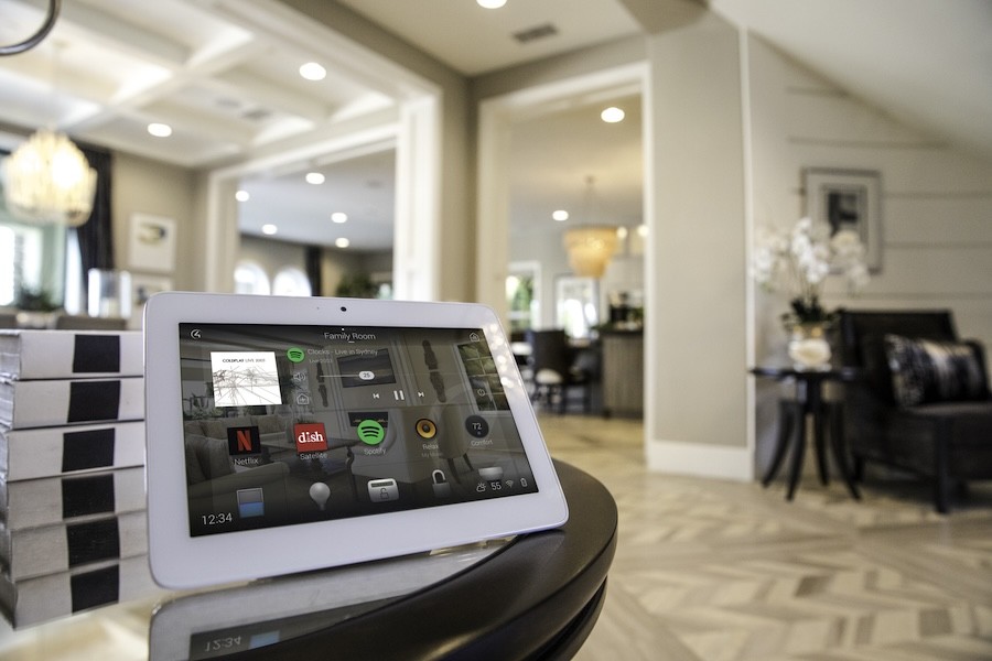  A control4 touchscreen resting on a table with the rest of the house in the background.